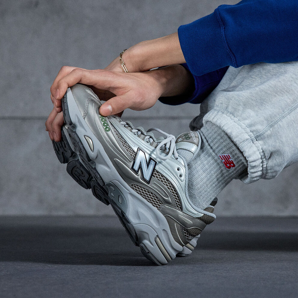 A  knee down shot image of an individual wearing a pair of New Balance 1000 sneakers 